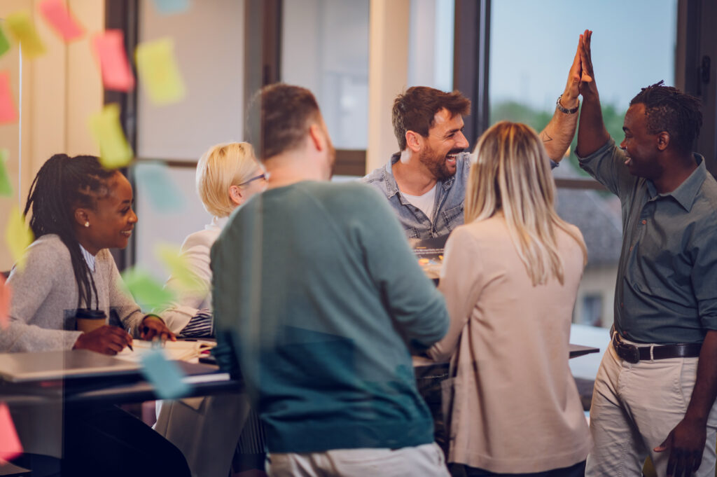 A multiracial team of professionals looking visibly joyful, working in a modern office setting